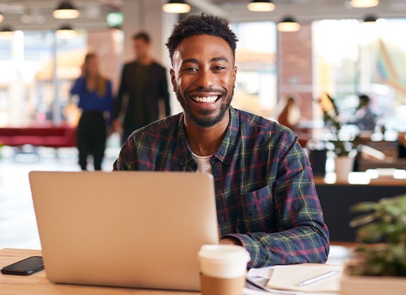 Man smiling while working on laptop
