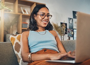 Woman smiling while working on laptop at home