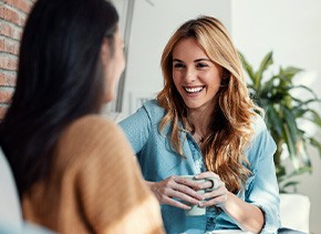 Woman smiling while drinking coffee with friend