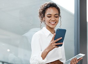 Woman smiling while looking at phone in office