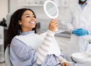 Woman smiling at reflection in handheld mirror