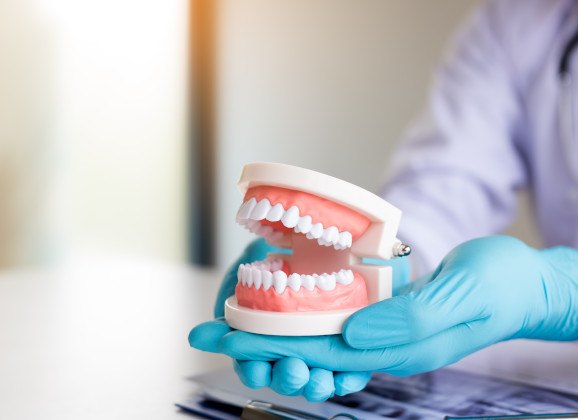 hand holding full denture in glass of water 