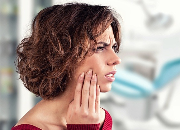 Woman in need of emergency dentistry holding cheek