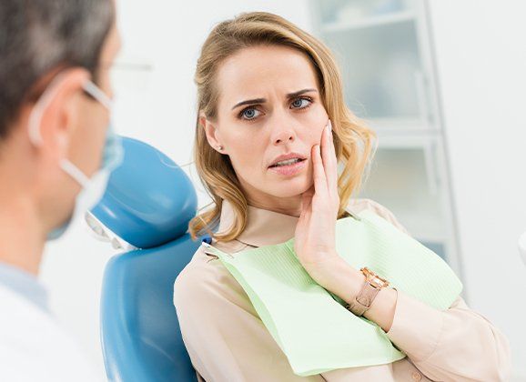 Woman in need of tooth extraction holding cheek