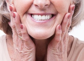 a woman pointing to her smile and holding dental implants  
