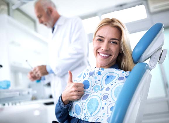 Woman giving thumbs up after root canal therapy in Brooklyn