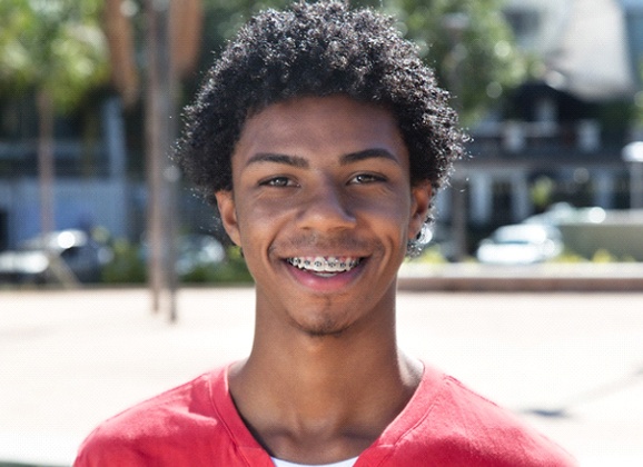 Man with braces smiles after visiting his Brooklyn orthodontist