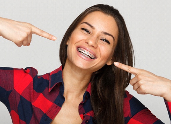 Woman points to her smile after visiting her Brooklyn orthodontist 