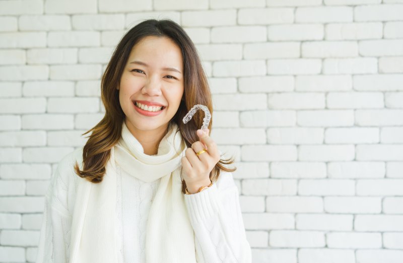 Smiling woman holding Invisalign tray