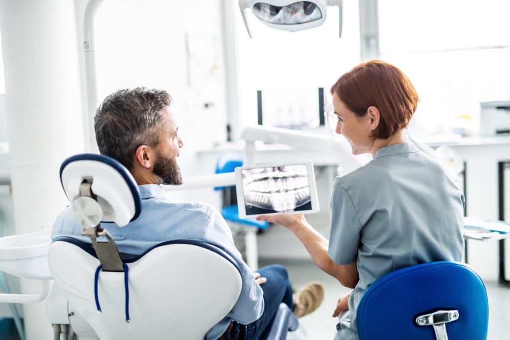 Dentist showing patient X-ray while discussing root canals