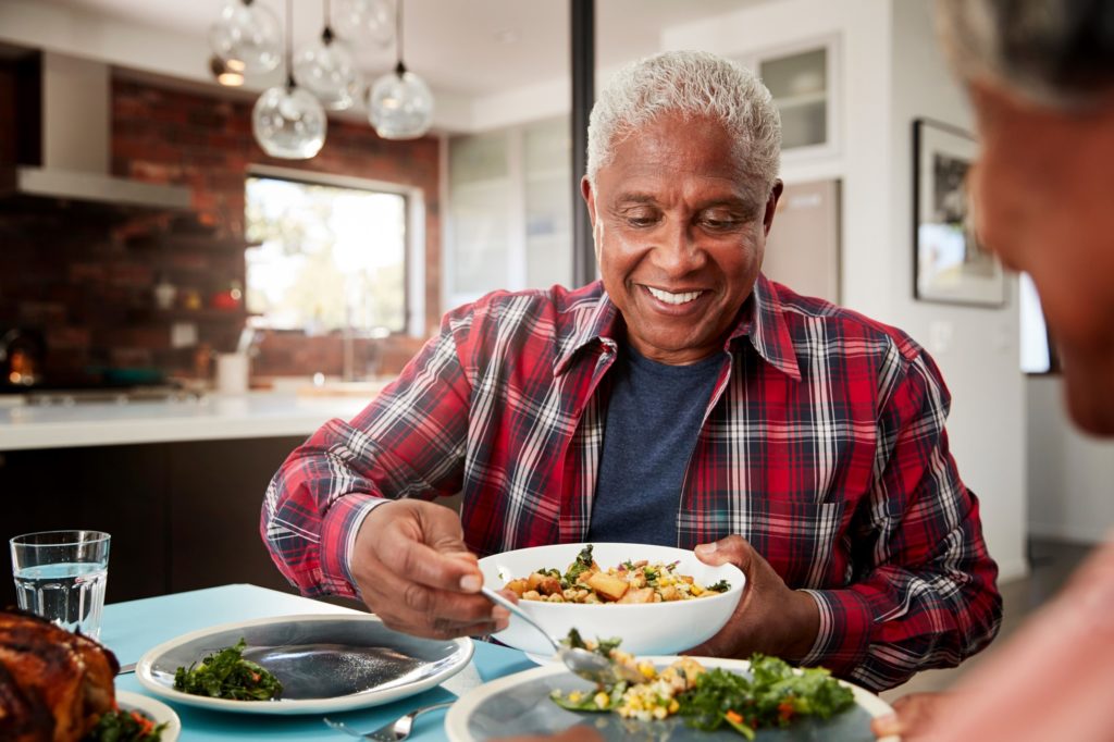 Man with dentures smiling while eating meal at home