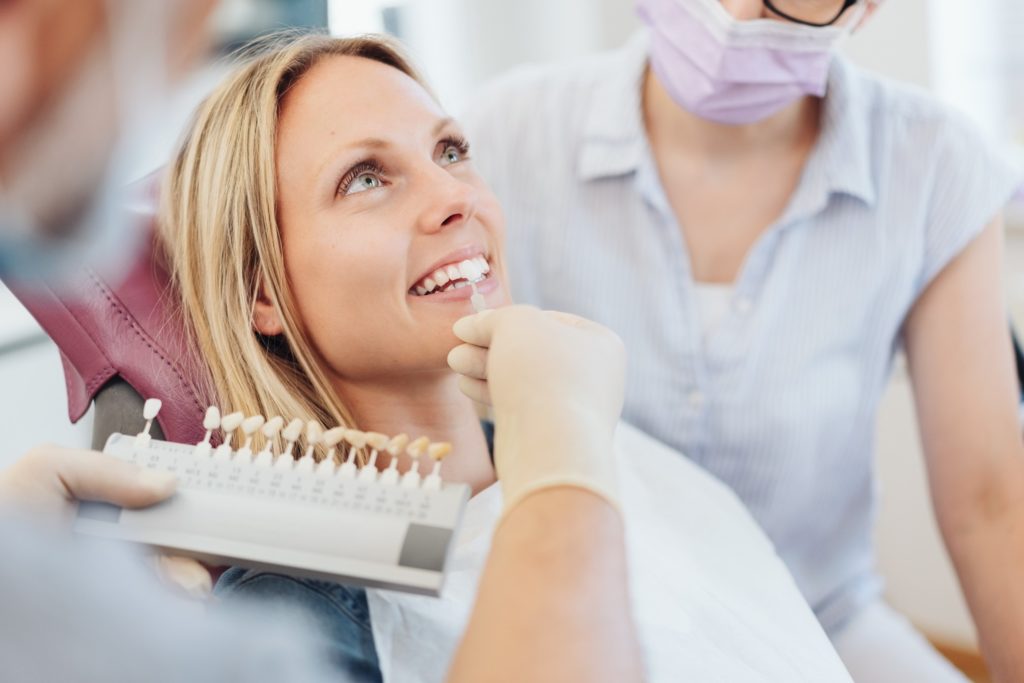 Patient smiling while dentist picks shade of veneer