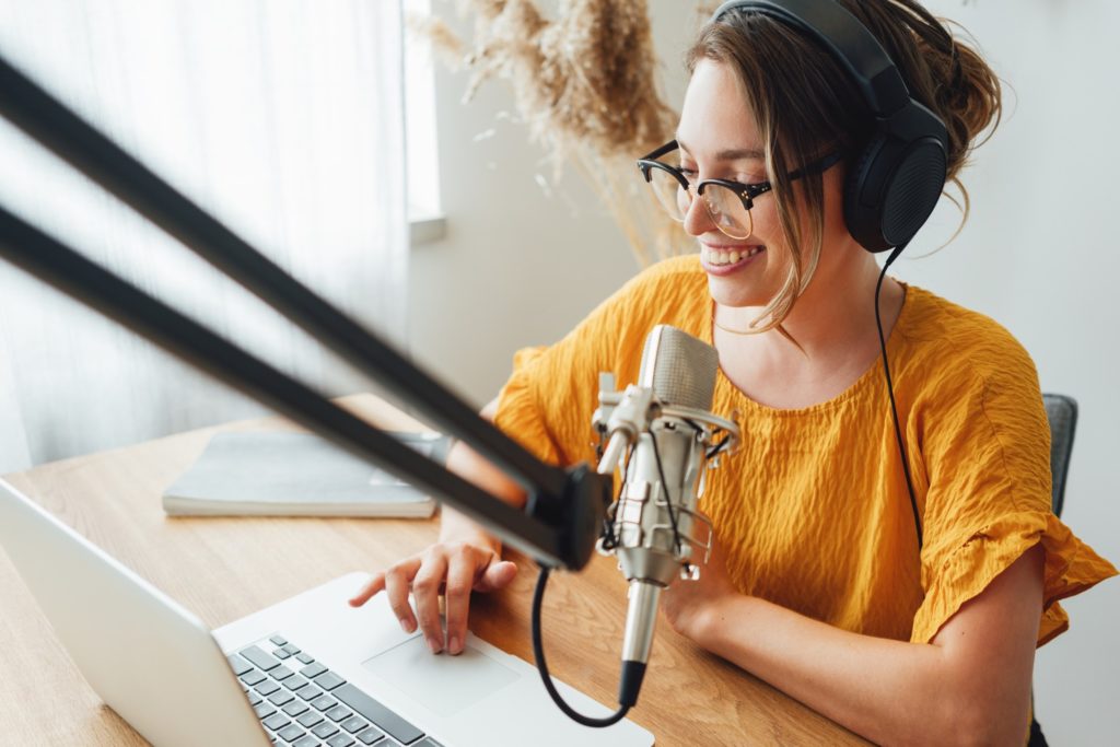 Woman smiling while working on podcast at home