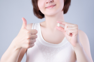 a patient holding a tooth and giving a thumbs up