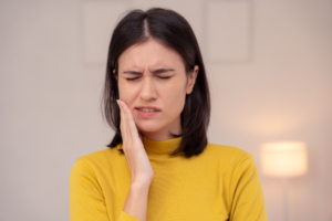 a woman holding her cheek in pain