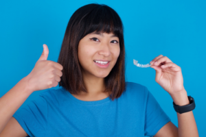 a teen holding their Invisalign and smiling